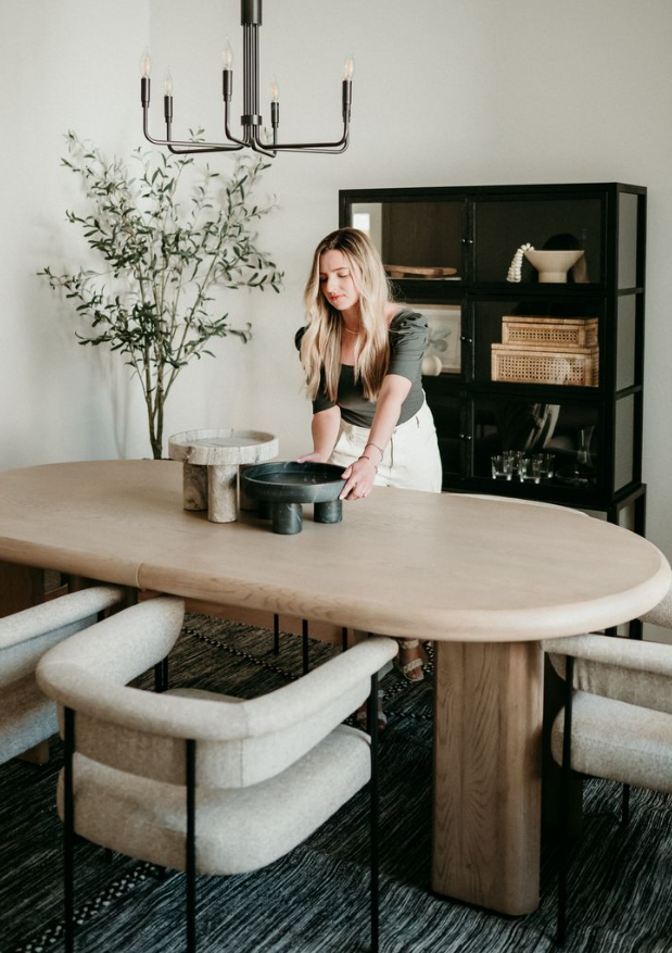 A stylist arranging a flower vase at a beautifully styled dining table